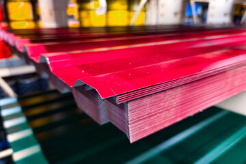 Metal roofing sheets stacked in a warehouse showcasing vibrant red color and unique corrugated design during daytime operations