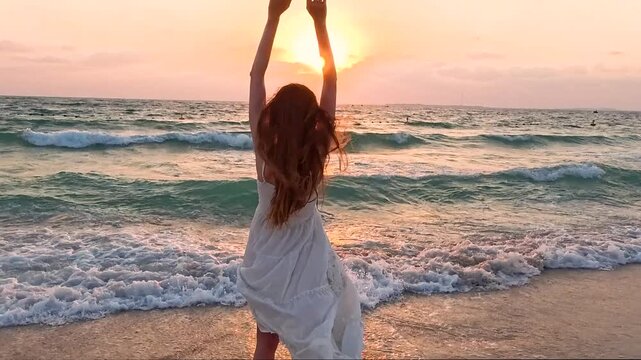 Woman in long white dress running towards the sea sunset on the seashore and raising her hands up, slow motion. Hope for the future, faith in oneself..