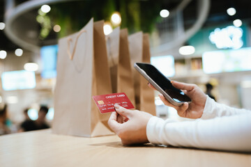 A beautiful young woman smiles while paying with a credit card at a café, embracing online shopping, finance, technology, and lifestyle.