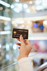 A beautiful young woman smiles while paying with a credit card at a café, embracing online shopping, finance, technology, and lifestyle.