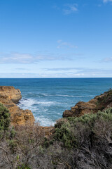 Blue Ocean Waves with Rocky Cliff and Green Bushes