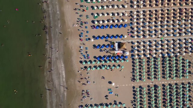 Aerial view of Rimini beach, Italy, with rows of umbrellas, sandy shore, and swimmers in the sea