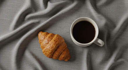 Crispy golden croissant and rich black coffee served on textured grey fabric, a perfect morning indulgence
