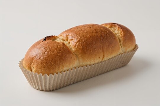 Bread dough shaped as a sausage inside an elongated paper mold for baking.