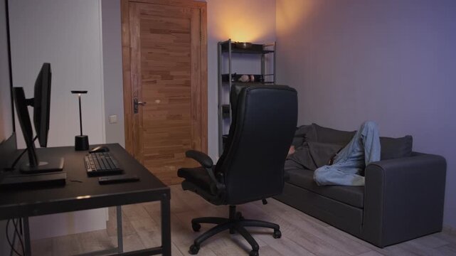 Young man finishing computer work rolling to sofa relaxing home authentic lifestyle