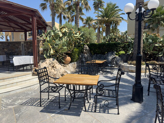 Relaxing outdoor restaurant scene with tables, chairs, and lush tropical plants. Perfect for summer vibes.