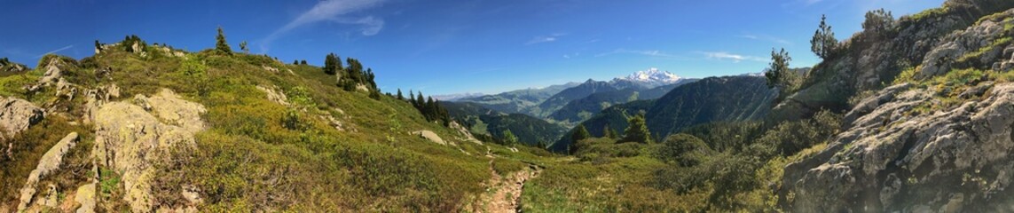 Panoramic landscape with mountains and greenery under a clear blue sky