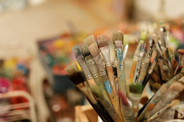 Close-up shot of various used paint brushes in an art studio.  Perfect for creative projects, art supplies, and artistic concepts.