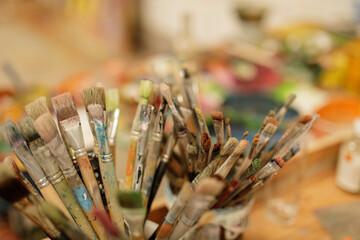 Fototapeta premium Close-up of a collection of well-used paintbrushes, showing paint splatters and textures. Perfect for art, creativity, and hobby projects.