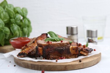 Roasted beef ribs with spices and ketchup on white table, closeup
