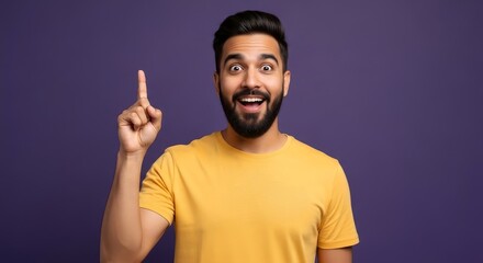 Man in yellow shirt pointing upwards with excited expression against a purple background idea moment
