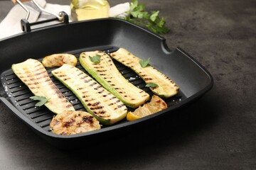 Delicious grilled courgette slices with garlic, lemon and parsley in pan on grey table, closeup