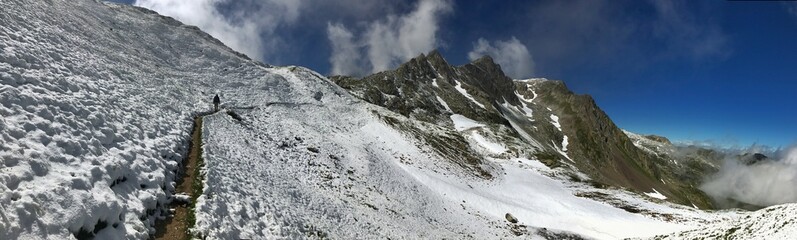 Panoramic view of snowy mountain trail with clear blue sky