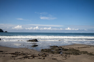 Scenic beach view with rocky shoreline, gentle waves, and clear blue sky
