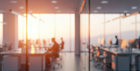Blurred office interior with people working at desks near large windows, surrounded by bright natural light, teamwork energy, and a modern collaborative workplace mood.