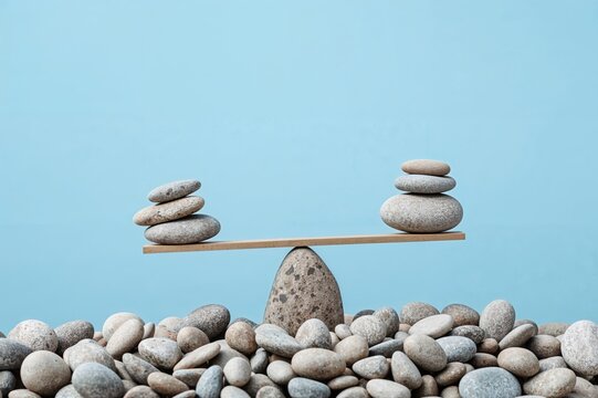 Stacked stones with scales symbolizing decision making and weighing pros and cons against a clear sky - Powered by Adobe