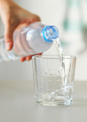 Clear water in a glass and bottle on the table. Vertical photo format
