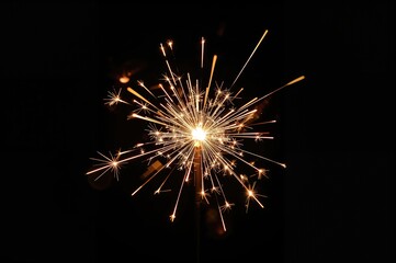 Fototapeta premium A glowing hand-held sparkler candle casting soft light on a transparent surface, evoking a festive atmosphere with vivid illumination effects.