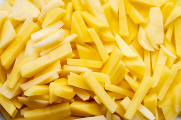 Raw potatoes cut into strips, close-up. Vegetable slices for cooking fried potatoes and French fries. Fresh farm products. Organic vegetarian ingredients