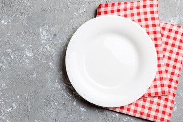 Top view on colored background empty round white plate on tablecloth for food. Empty dish on napkin...
