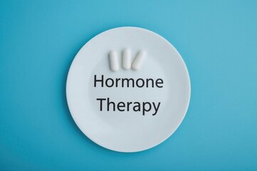 Healthcare and Medicine Theme with Pills on a Blue Surface Featuring the Words 'Hormone Therapy' on a Dish