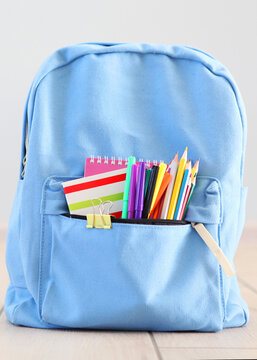 School backpack and stationery in a bright room.. Vertical photo format