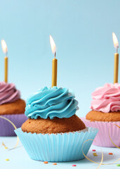 Delicious cupcake with a candle on a colored background. Vertical photo format