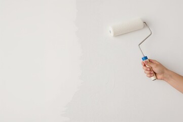 Worker applying white paint on wall using roller brush, apartment renovation in progress with blank space for text
