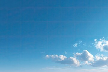 Clear, vibrant blue sky with scattered, fluffy white clouds