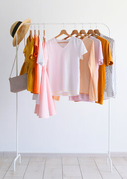 fashionable clothes on a rack in the interior of a bright room. Vertical photo format