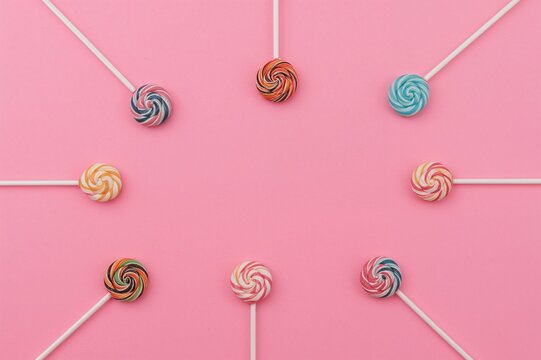 Colorful lollipops in bright and soft shades arranged perpendicularly on a pink surface