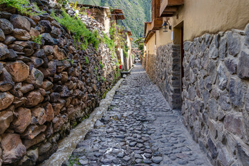 Obraz premium Traditional narrow alleyway with ancient Inca stone walls and cobblestone pavement in the historic town of Ollantaytambo, Peru.