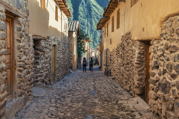 Traditional narrow alleyway with ancient Inca stone walls and cobblestone pavement in the historic town of Ollantaytambo, Peru.