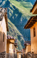 A picturesque view of a narrow street with traditional tiled roofs houses in the historic village of Ollantaytambo, Peru.