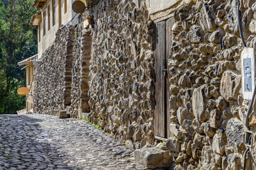 Traditional narrow alleyway with ancient Inca stone walls and cobblestone pavement in the historic town of Ollantaytambo, Peru.