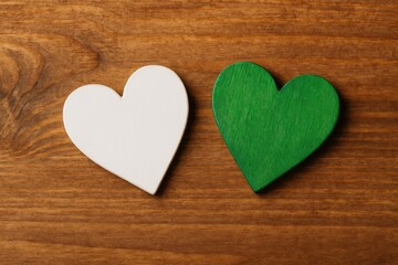 Obraz premium A pair of wooden hearts painted white and green resting on a wooden background