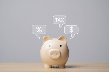 Piggy bank with speech bubbles showing tax, dollar sign, and percentage on wooden table. Concept of...