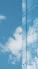Obraz premium Modern glass skyscraper reflecting blue sky and white clouds. Clean architectural minimalism with a sharp vertical composition and soft natural light.