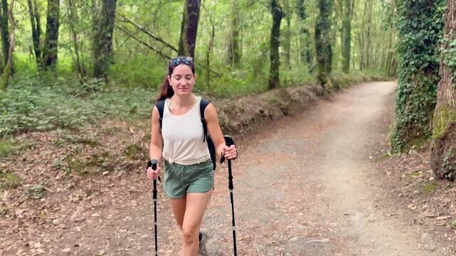 Young woman walking the Camino de Santiago from Sarria, joyfully exploring forest trails and city streets during her spiritual and cultural pilgrimage in northern Spain