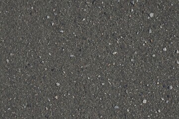 Detailed texture of coarse gray asphalt pavement with fine gravel elements, ideal for design use.