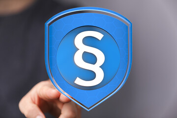 Abstract image of a digital shield with a legal paragraph symbol, representing security and legal...