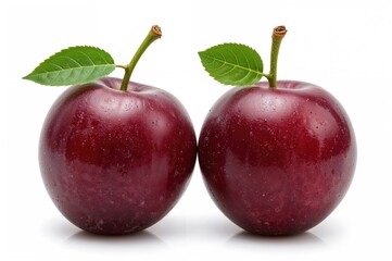 Two purple plums with foliage on a plain white backdrop