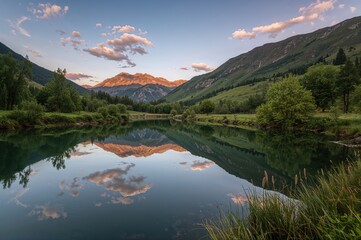 Fototapeta premium Sunset Over a Pond Reflecting Mountain Peaks Amid Lush Greenery in a Remote Mountainous Area
