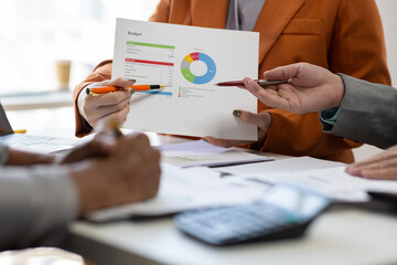 Business people analyzing financial chart and business data on office desk. Business colleagues reviewing financial reports and analyzing statistical charts during a meeting.