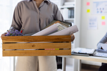 Employee leaving office carrying box with belongings after quitting job.