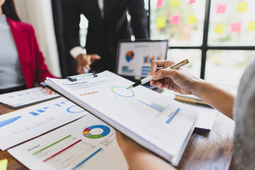 Business people analyzing charts and graphs, discussing financial report  using laptop and documents during a meeting in office.