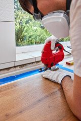 repairman using electric jigsaw and cutting hole for the sink in the kitchen countertops