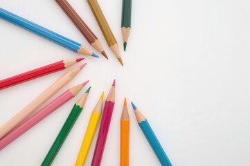 Fototapeta premium Colored pencils on a plain white surface, viewed from above.