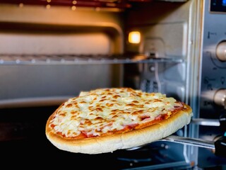 Fresh hot pizza being lifted from the oven, steaming and ready to serve.