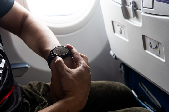 Passenger adjusting wrist watch to new time zone in airplane during long haul flight
